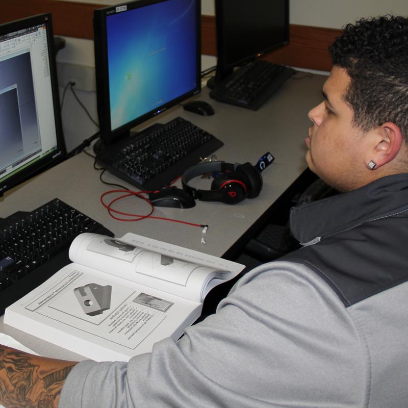Student working with book and computer